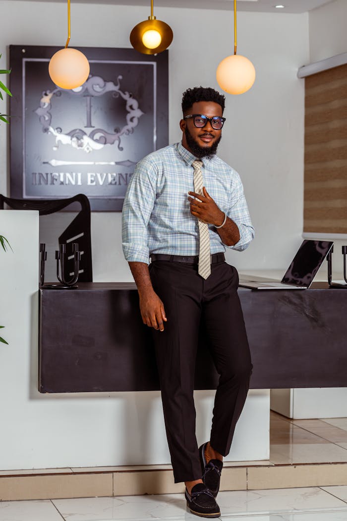 Stylish man posing in office setting, showcasing modern business attire with a confident demeanor.